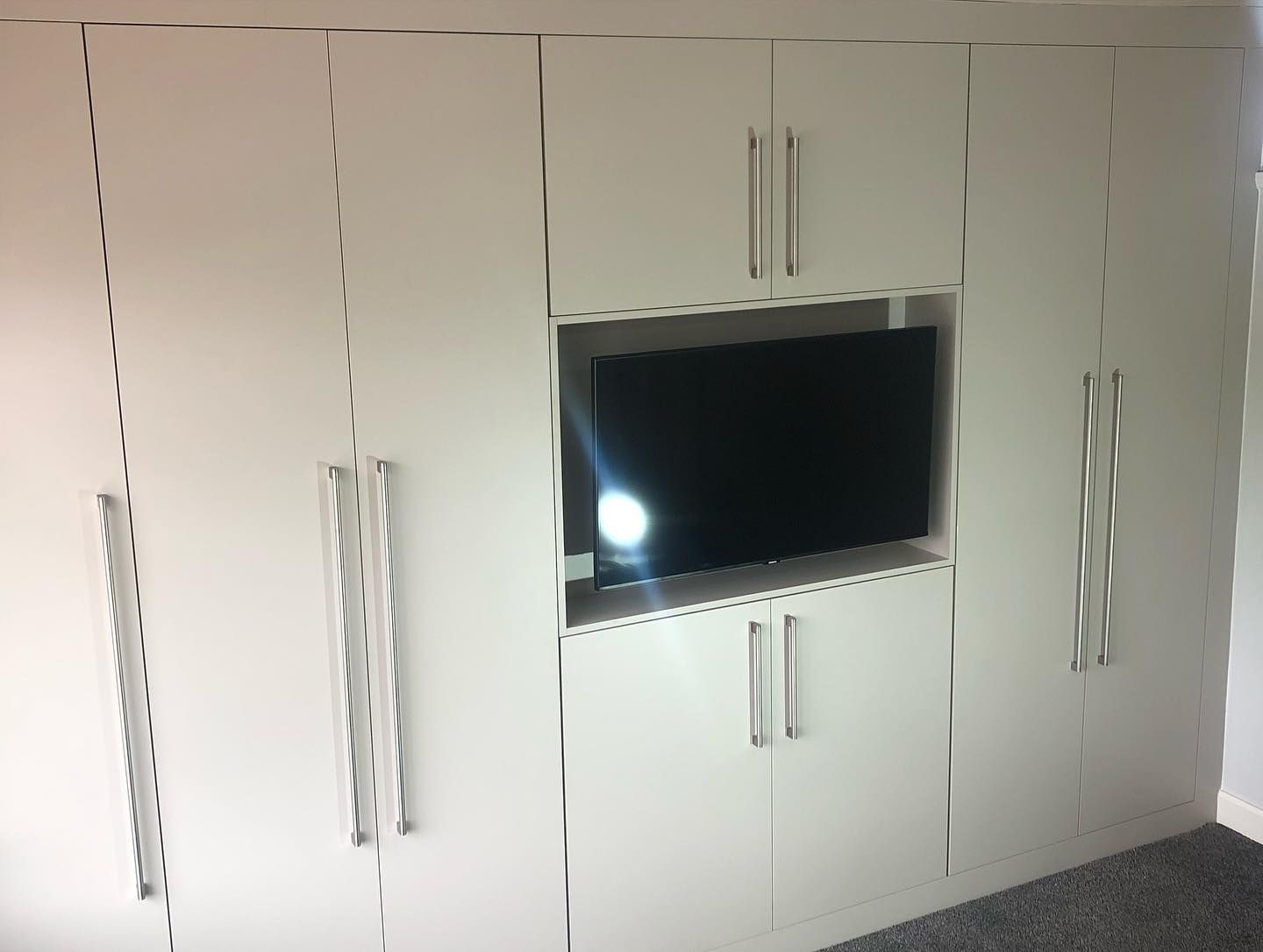 Wall of cashmere fitted wardrobes with a built-in television