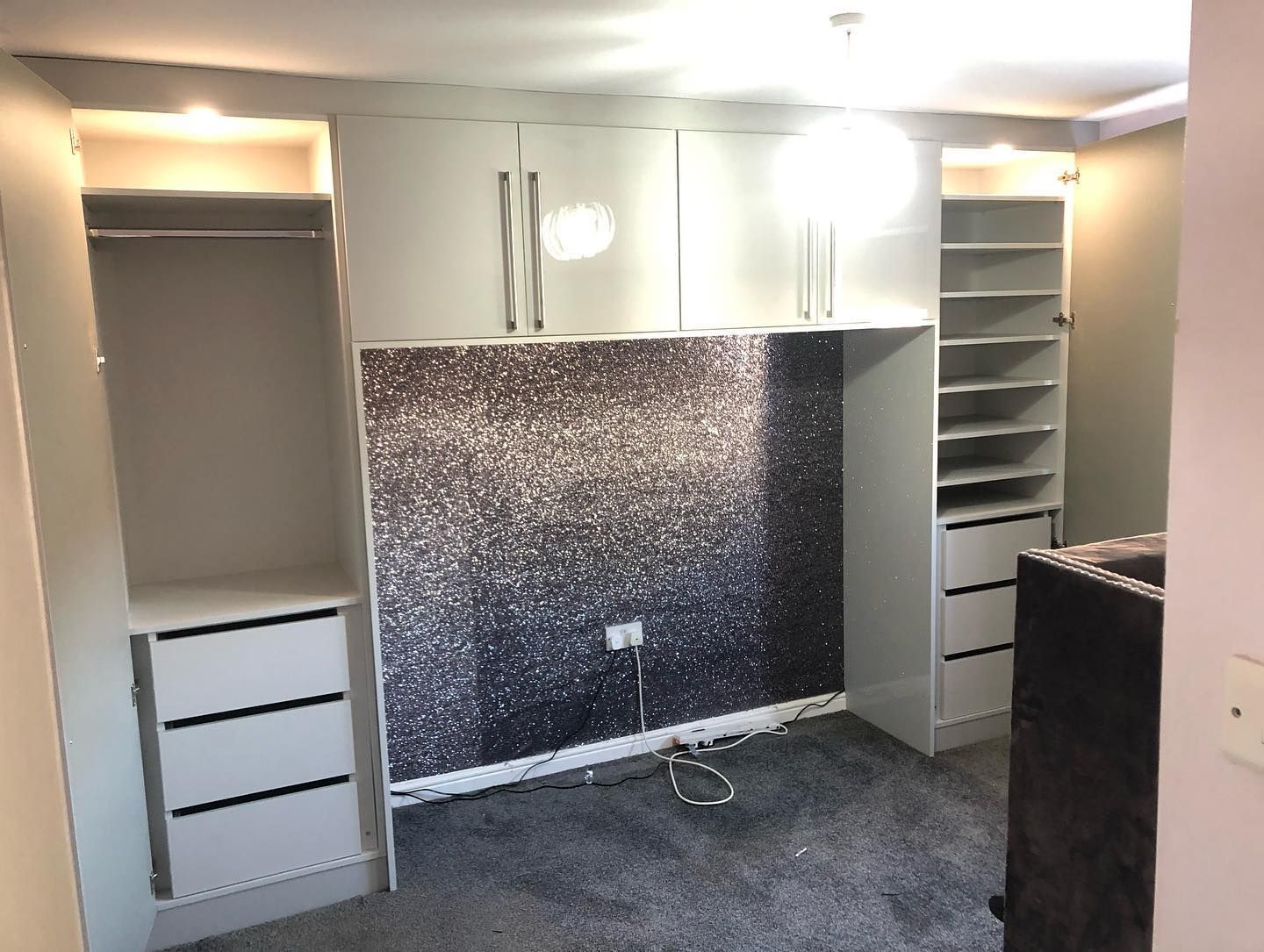 Light grey gloss fitted wardrobes and drawers around a feature wall